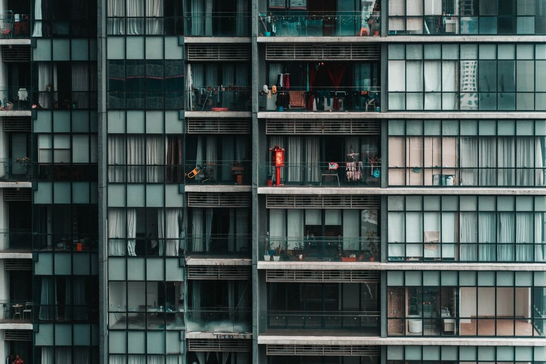 Fachada de edifício residencial com varandas e janelas onde redes de proteção são instaladas