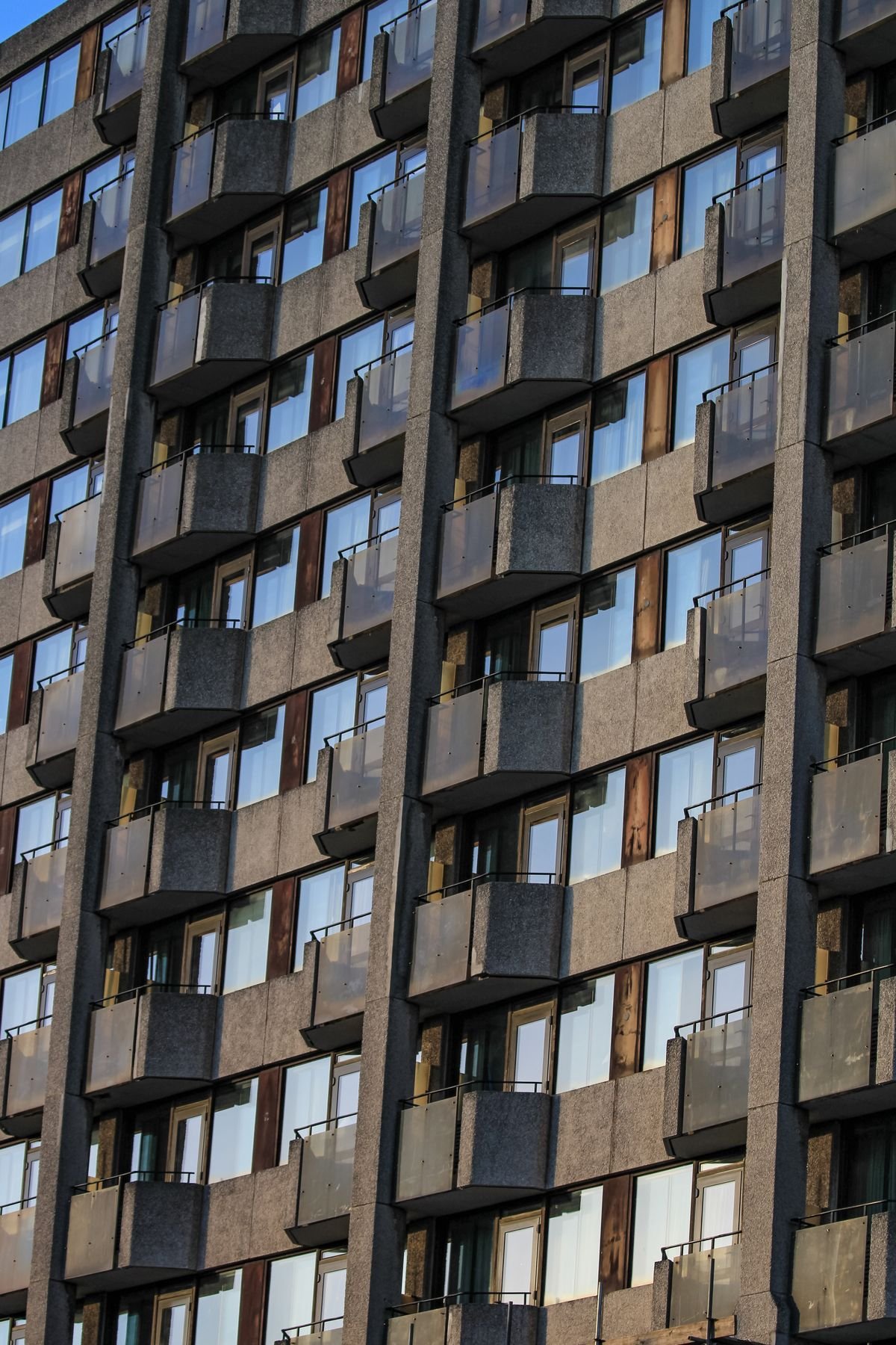 Fachada de prédio residencial moderno com varandas e janelas de vidro, contexto típico de apartamento que precisa de rede de proteção