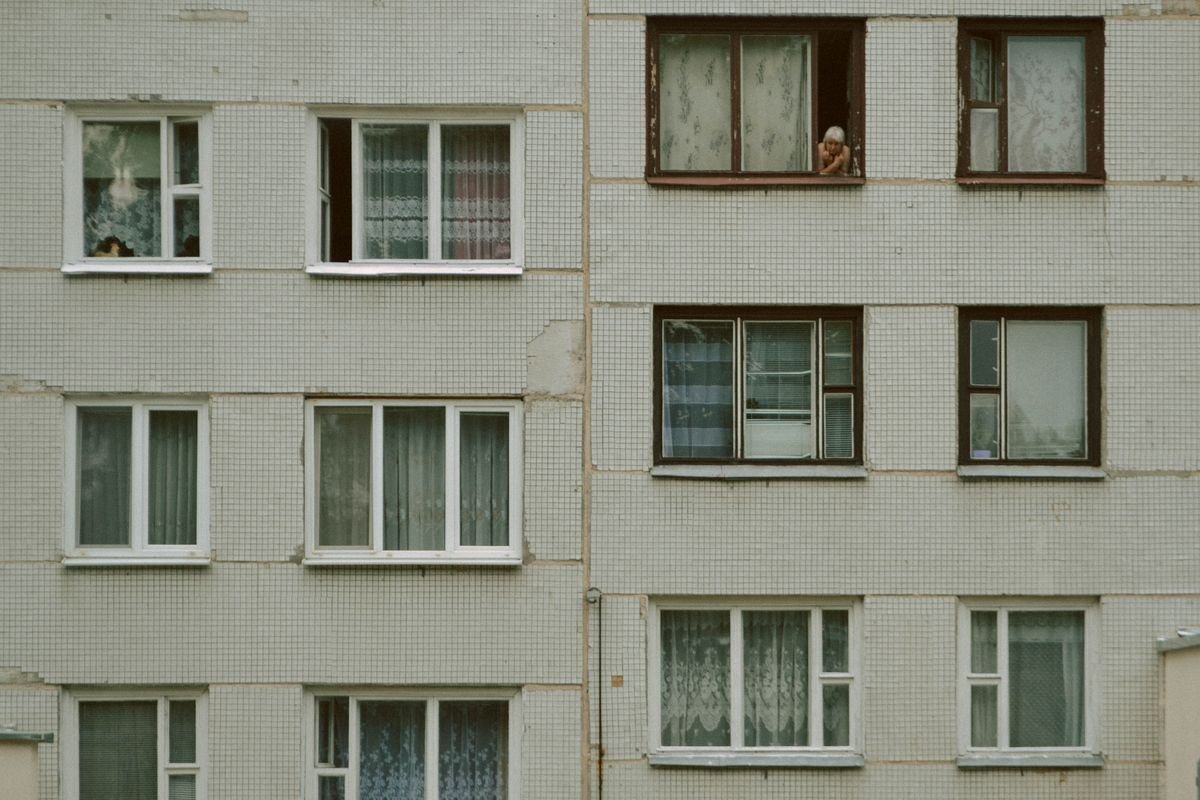 Pessoa olhando pela janela de um apartamento, contexto de segurança residencial