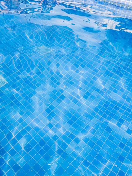 Água transparente de piscina sobre azulejos azuis